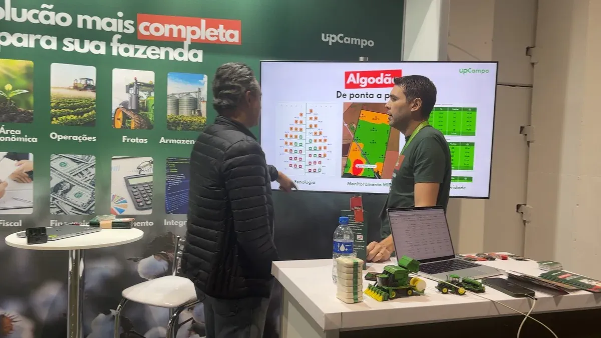Dos hombres conversan frente a una exhibición de algodón en una feria de tecnología agrícola