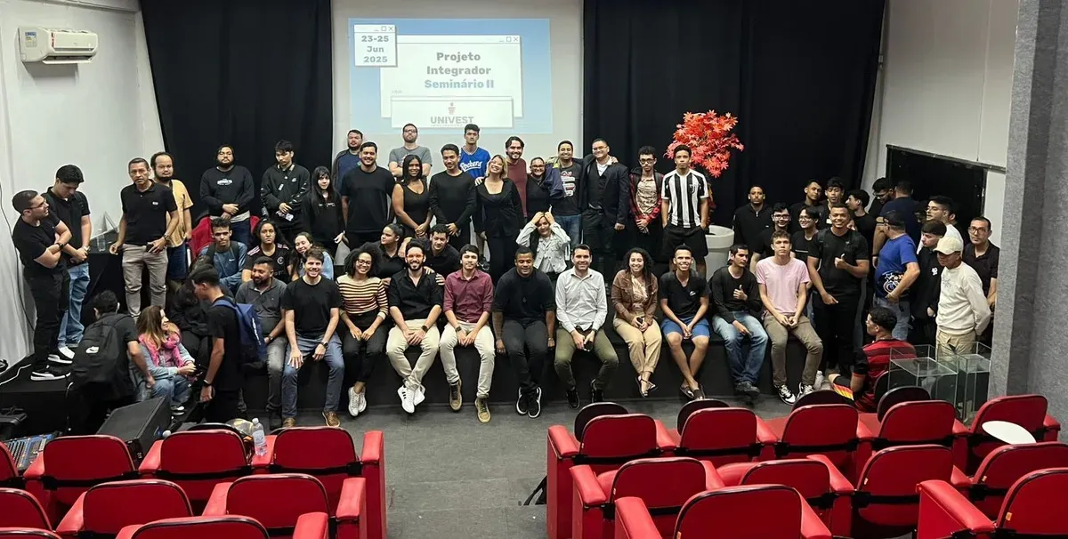 Grupo de personas en un auditorio de Univest, con la proyección del Proyecto Integrador al fondo