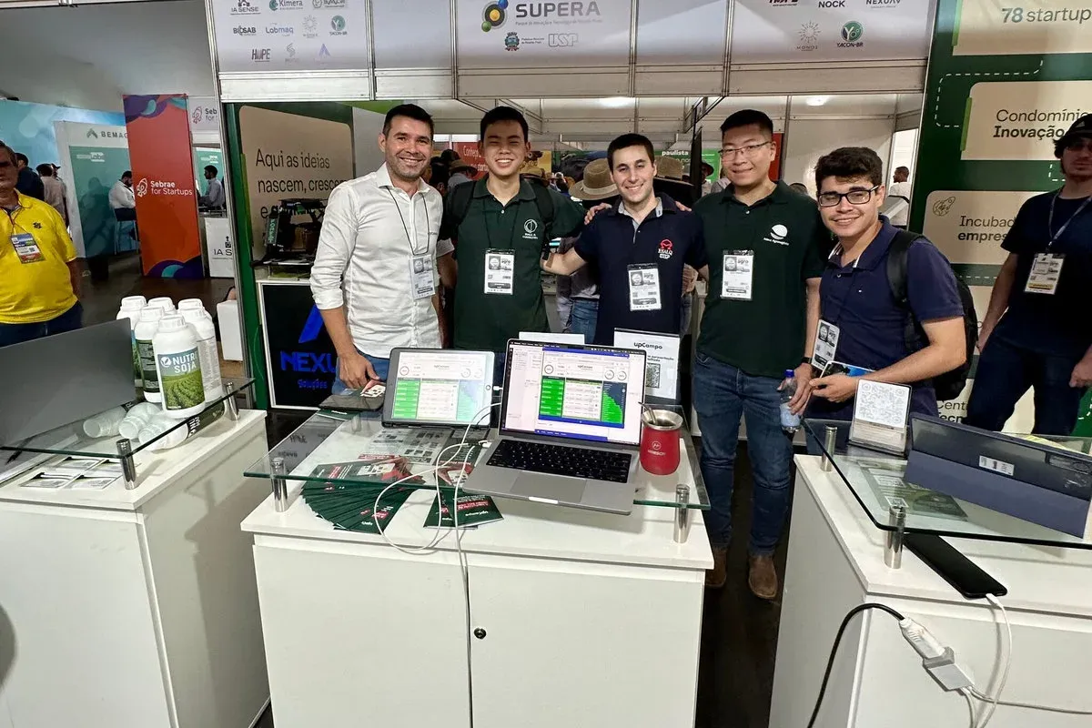 Equipo de upCampo atendiendo a visitantes en el stand, con el sistema abierto en los monitores