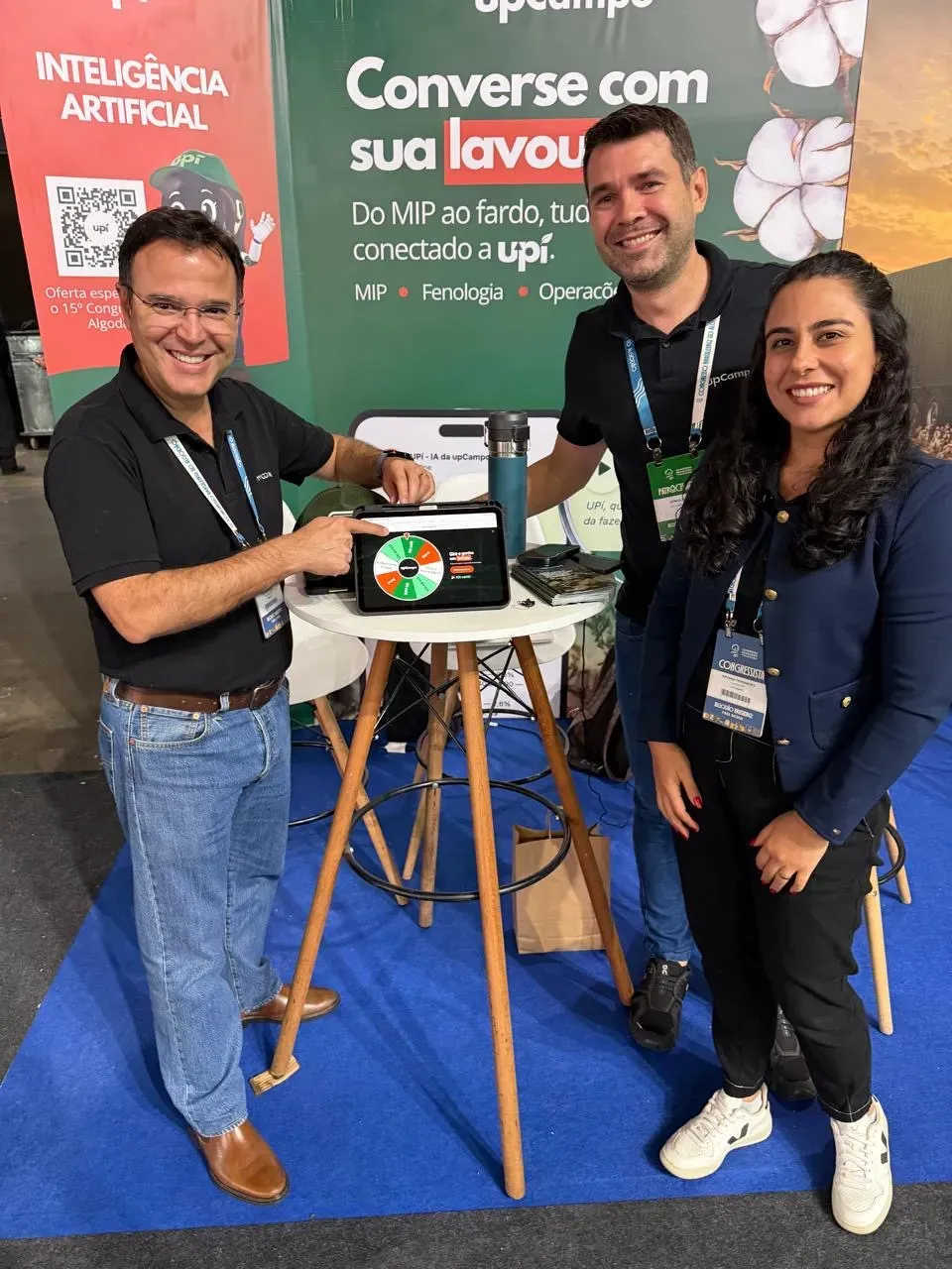 Equipe da upCampo com um visitante no estande, com o tablet sobre a mesa